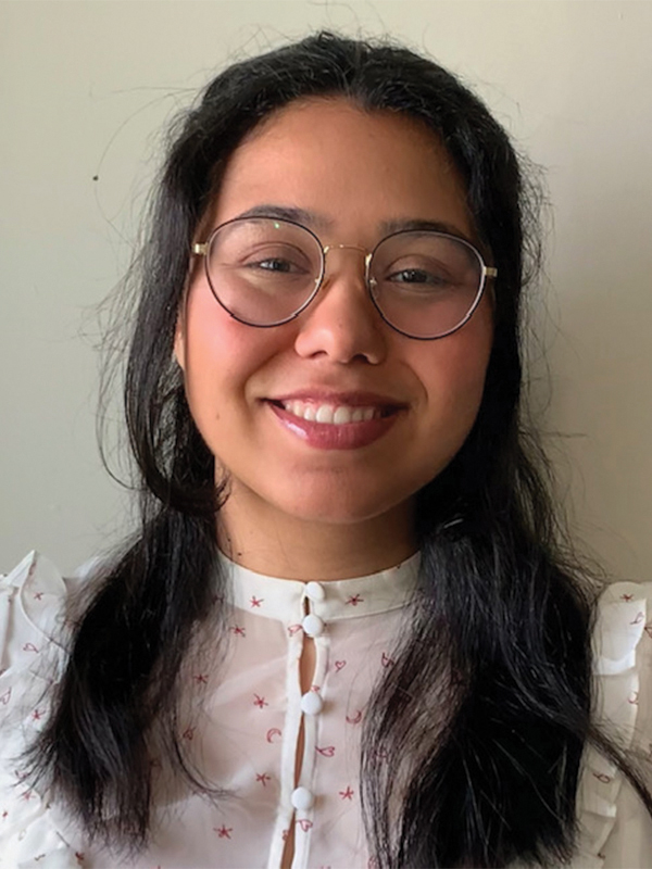 A headshot of a woman with glasses and a floral blouse smiling into a camera